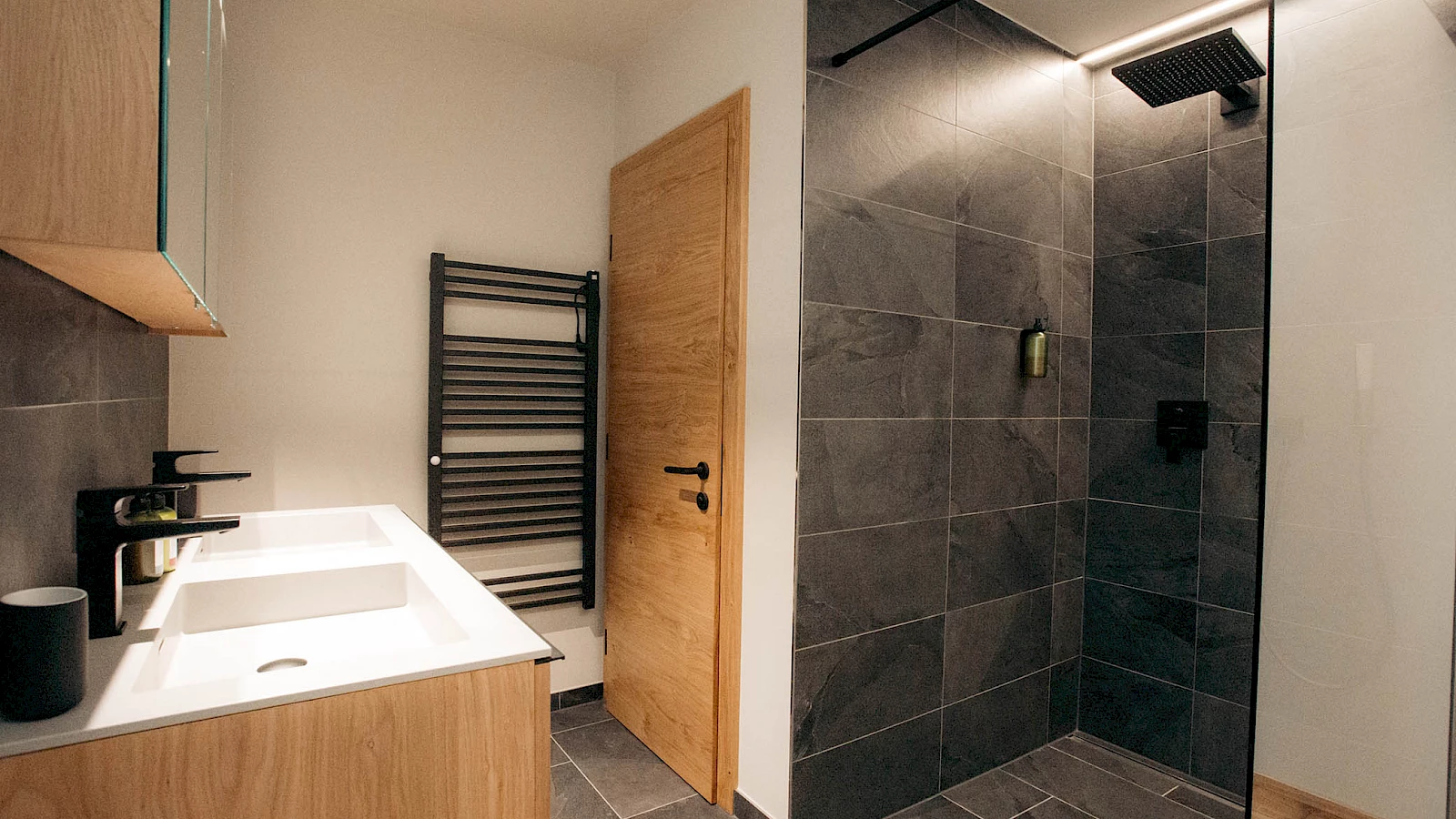 Badezimmer mit Doppelwaschbecken, Dusche und Toilette in der Ferienwohnung Ischgl.